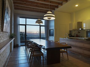Large wooden dining table in kitchen at sunset