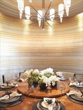 Circular dining table and striped wall paper in modern dining room