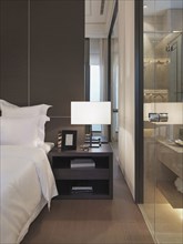 Nightstand and lamp beside bed in modern bedroom