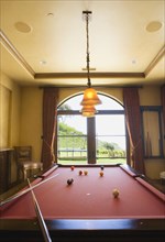Red Pool Table and Balls with Overhead Lights and Window