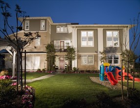 Exterior of attached homes in the evening with playground