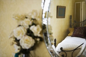 Detail of white roses next to antique vanity mirror.
