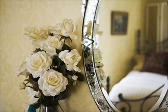 Detail of with white roses next to antique vanity mirror.
