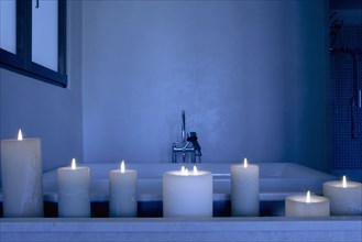 Night scene with a collection of lit candles in front of a bathtub