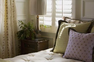 Purple and green decorative pillows on bed near window