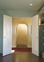 Open double doors leading to an upward staircase