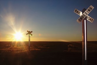 Railroad crossing sign on remote road at sunset