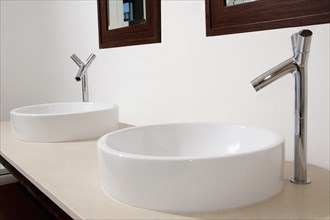 Close up of sinks and faucets in modern bathroom