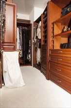 Shelves and hanging clothes in walk-in closet
