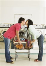 Asian couple kissing in laundromat