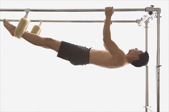 Asian man hanging on exercise equipment