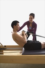 Instructor helping man on exercise equipment