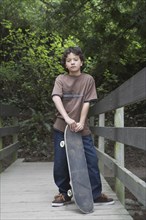 Mixed race boy standing with skateboard
