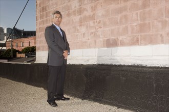 Portrait of confident Hispanic businessman standing near brick wall