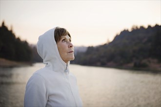 Caucasian woman wearing hood near lake