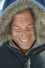 Smiling Caucasian man wearing coat with fur hood
