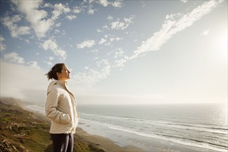 Mixed Race woman standing on beach admiring ocean