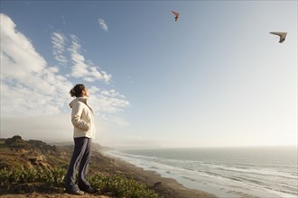 Mixed Race woman standing on beach watching gliders