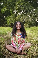 Portrait of smiling mixed race woman sitting in grass