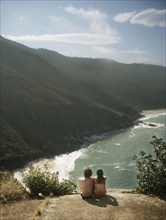 Couple sitting on cliff over ocean beach