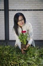 Asian woman planting flower in garden
