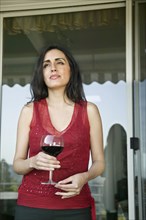 Pensive mixed race woman drinking wine