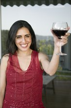 Mixed race woman toasting with wine