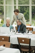 Business people using laptop at restaurant