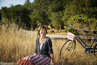 Laughing Caucasian woman sitting near bicycle