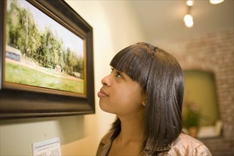 Mixed race woman admiring painting in gallery
