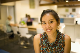 Smiling Asian businesswoman in communal workspace