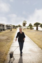 Senior Caucasian woman walking dog on sidewalk