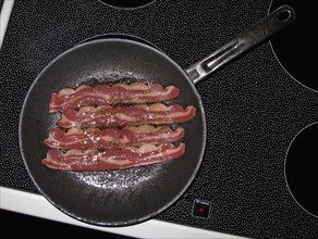 Bacon frying in pan on stove top