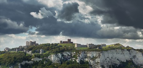 Town built on white cliffs under stormy sky