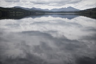 Cloudy sky reflected in still rural lake