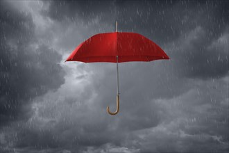 Red umbrella floating in storm clouds