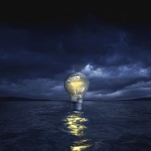 Illuminated light bulb floating in sea