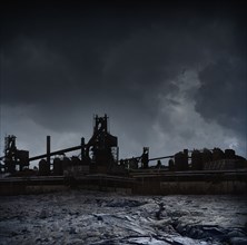 Silhouette of factories against stormy sky