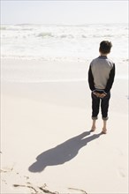 Boy standing on sunny beach