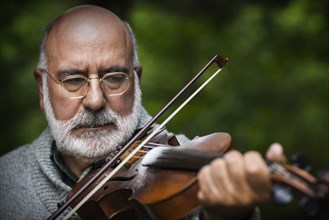 Senior Caucasian man playing violin outdoors