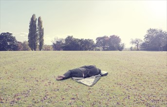 Man napping on coat in park field