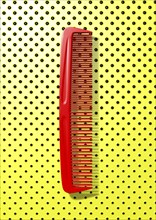 Close up of red comb on polka dot background