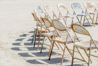 Dilapidated chairs arranged in circle in dirt field