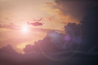 Silhouette of helicopter flying in cloudy sky