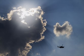 Low angle view of helicopter flying in cloudy sky