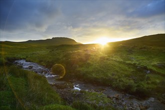 Sunrise over rural hills and stream