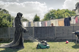Grim Reaper mowing backyard
