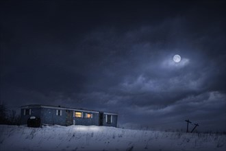 Moon over trailer house in snowy yard