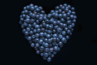 Blueberries in shape of heart on black background