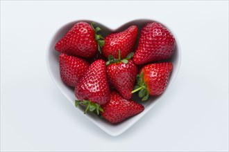 Strawberries in heart-shape bowl on white background